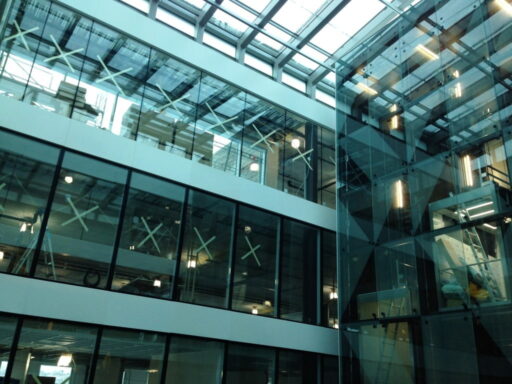 Innvendig atrium med store glassvinduer og tak i moderne bygg.
