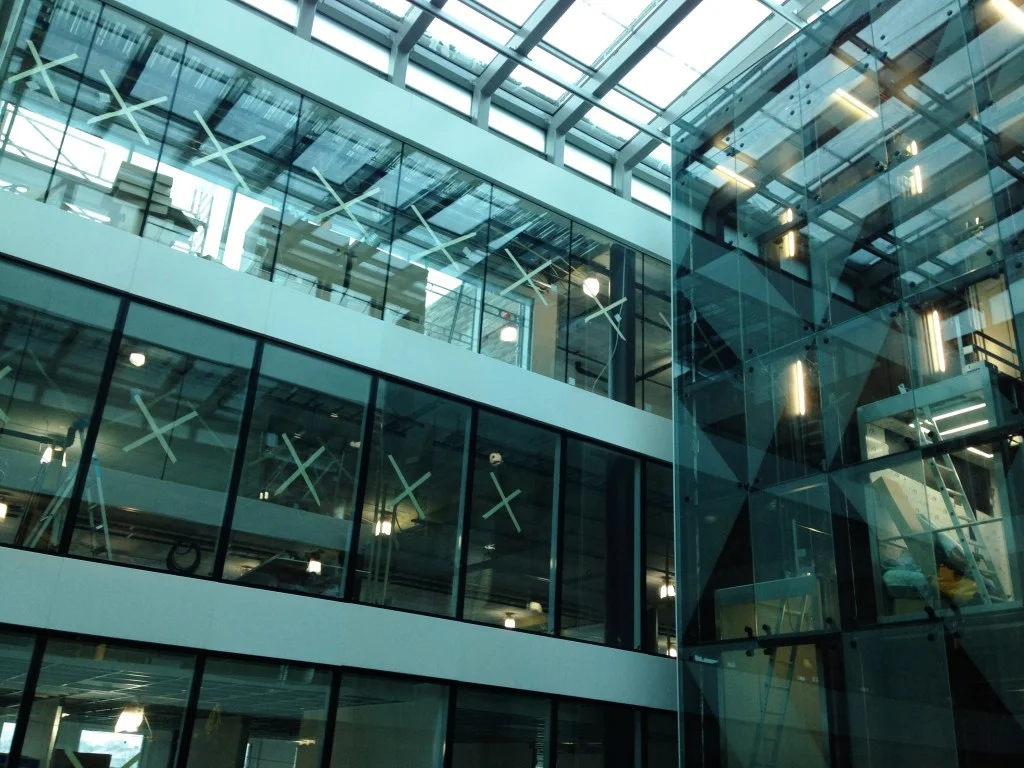 Innvendig atrium med store glassvinduer og tak i moderne bygg.