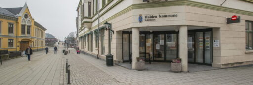 Inngang til Halden kommune rådhus ved brosteinlagt gate.