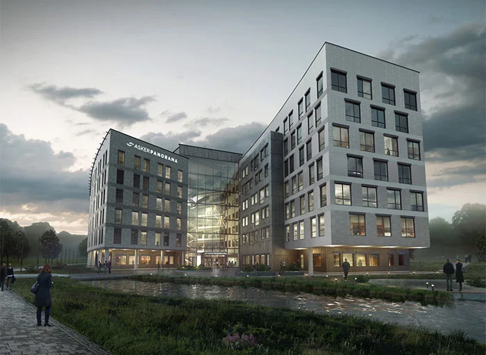 Moderne kontorbygg med glassfasade og grønt område foran.