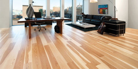 Moderne kontor med stort skrivebord, skinnsofa og lyse tregulv