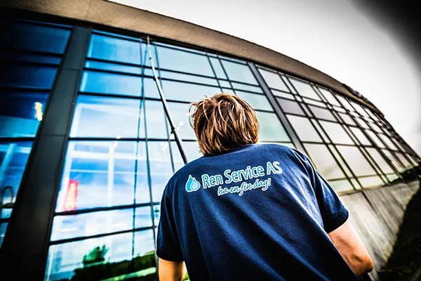 Person med Ren Service AS t-skjorte foran stor glassfasade.