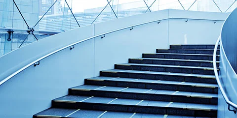 Moderne trapp med glassrekkverk i lys bygning.