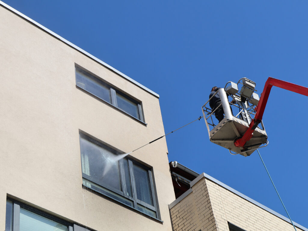 Person tørker toppen av en vaskemaskin med blå klut.